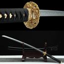 Golden ornate tsuba on black fabric handle with full katana and scabbard placed on wooden stand. Kuro Katana collection.