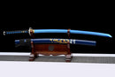A blue katana with a black handle and a detailed dragon design on the scabbard, resting on a wooden stand. Aoi Ryū Katana.
