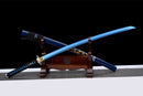 A vibrant blue katana displayed at an angle on a wooden stand; intricate gold dragon detailing on the scabbard. Aoi Ryū Katana.