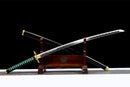 A Tokito Muichiro Katana displayed on a wooden stand, featuring a black and green handle, engraved silver blade, and black scabbard.