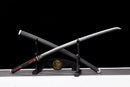 A black-handled katana with silver accents on a stand featuring a gold dragon design, sheathed in a black scabbard. Tanjiro Katana.