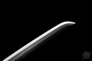 Sleek close-up of a katana blade tip with a sharp, shiny edge against a black background, showcasing craftsmanship. Tanjiro Katana.